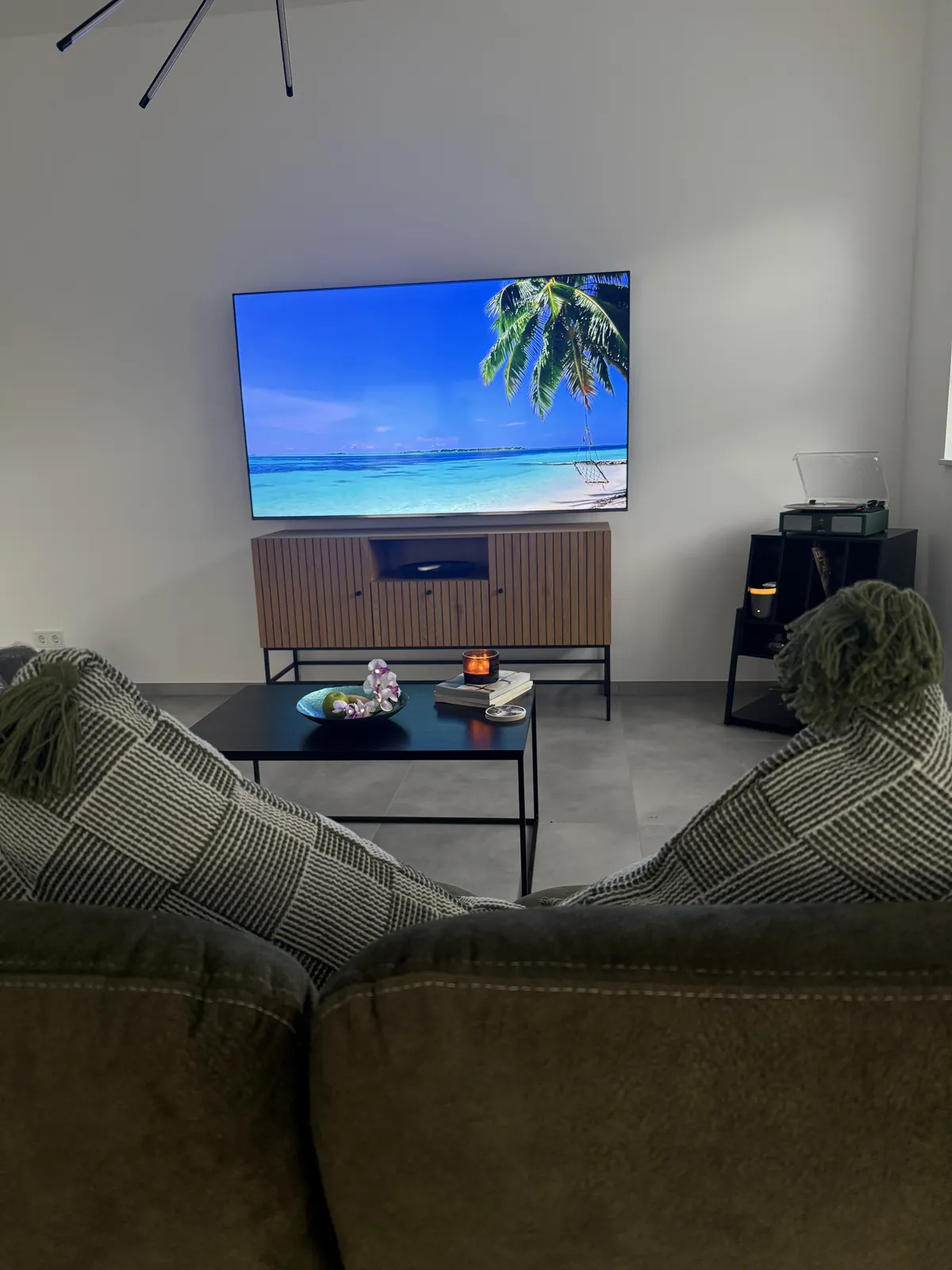 Wohnzimmer im Apartment auf Zeit in Hagen, modernes Design mit 75-Zoll-Smart-TV und hohen Decken